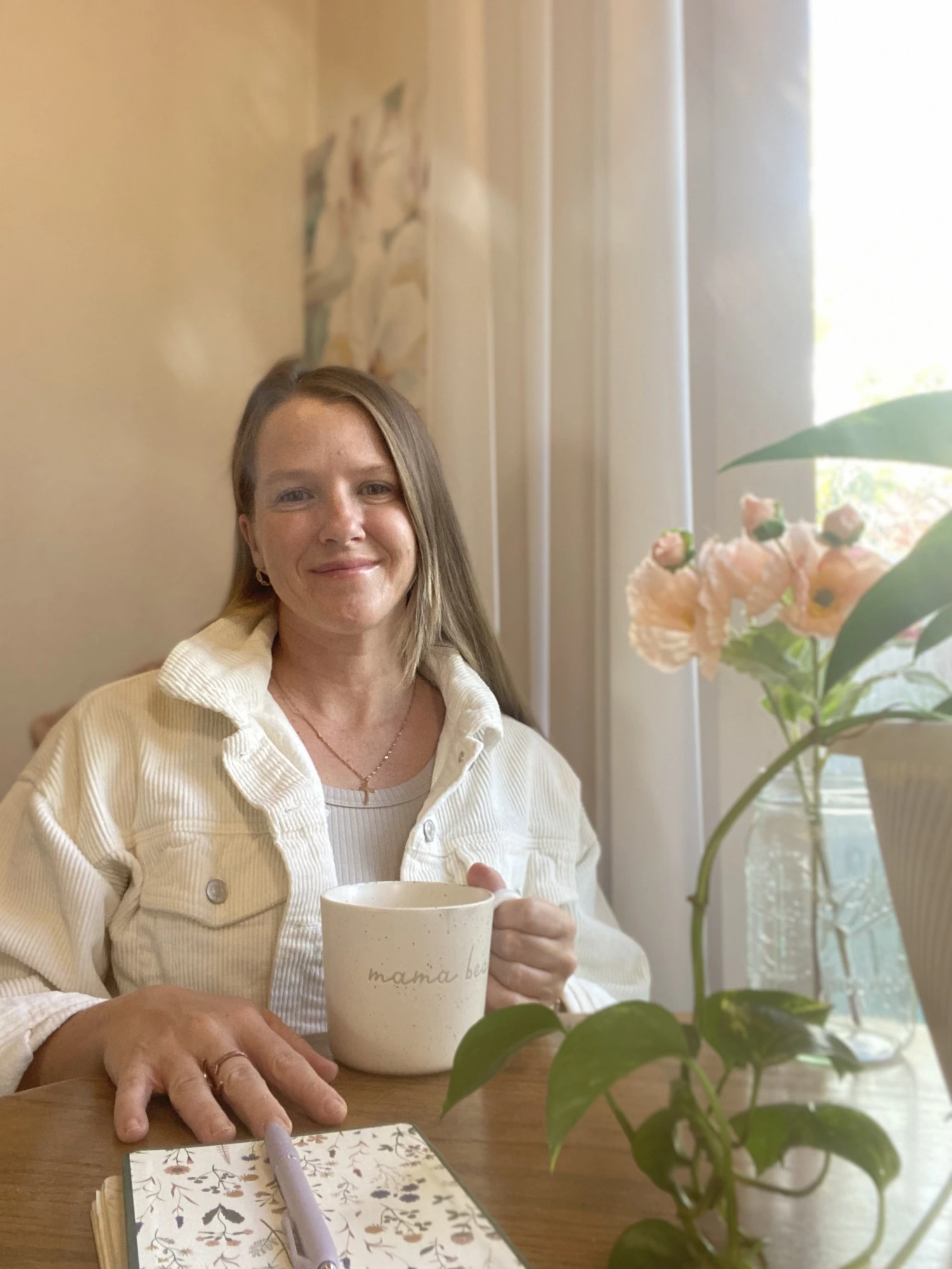 Andrea Hurley, certified pediatric sleep consultant, seated at a wooden table with a coffee and an open notebook